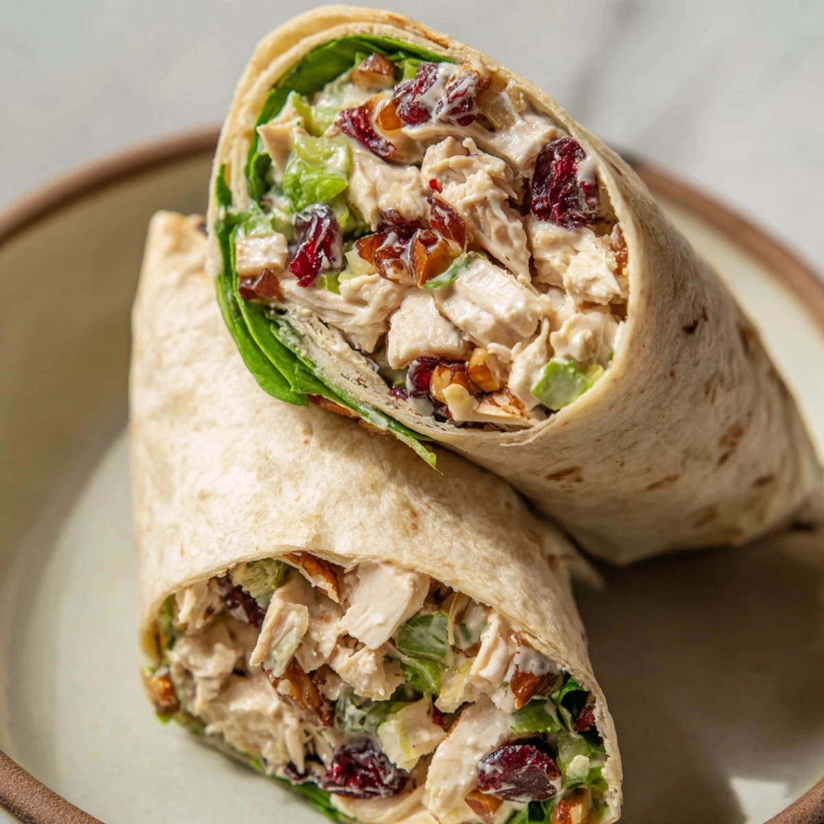 Close-up of a perfectly sliced Cranberry Pecan Chicken Salad Christmas Wrap, showcasing the colorful filling and fresh greens.