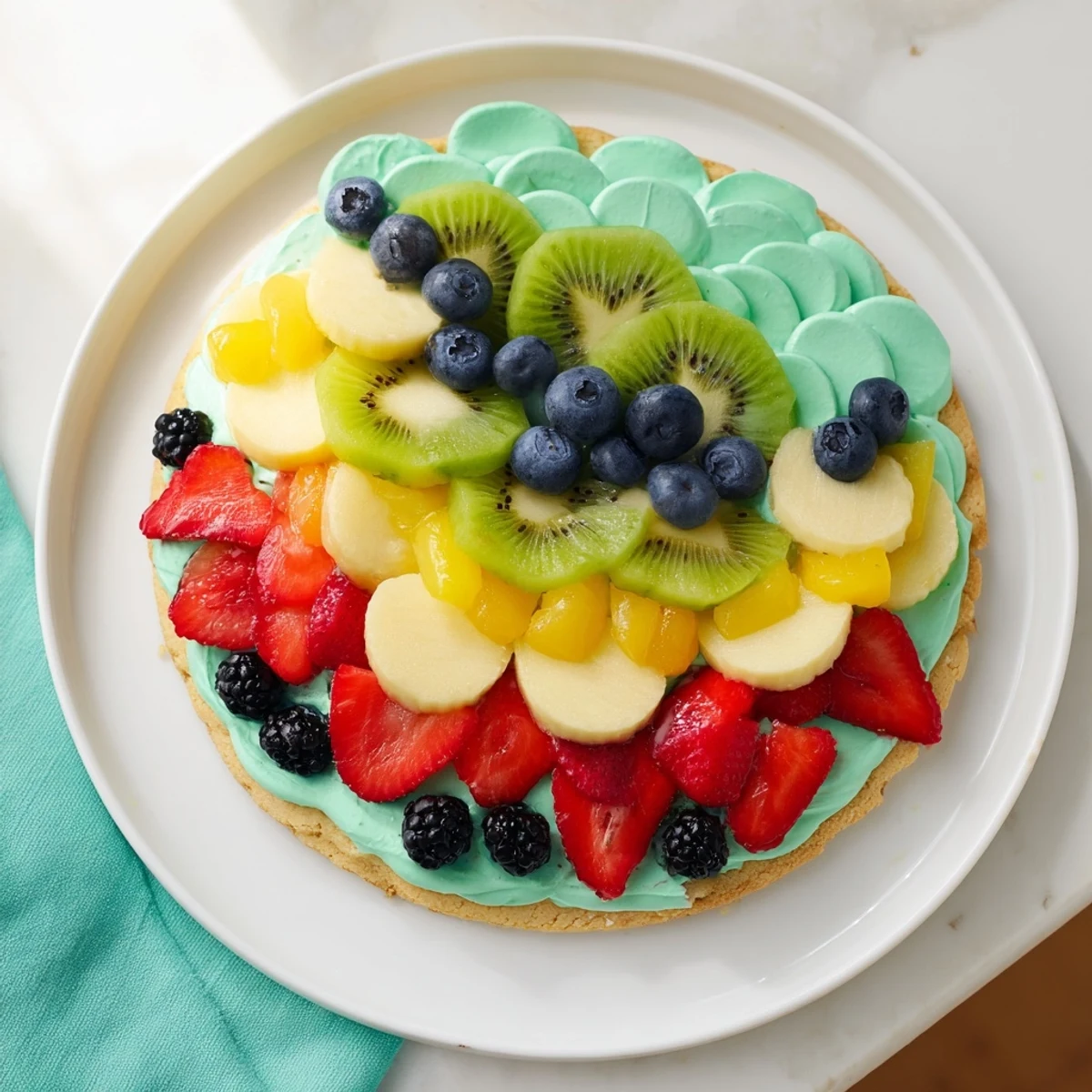 This Under the Sea: Mermaid Tail Fruit Pizza, with its creamy frosting and fruity scales, is ready to slice and enjoy.