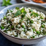 A fragrant rice pilaf with sweet spring peas, fresh mint, and bright lemon zest, served as a vibrant vegetarian side dish.
