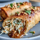 Crunchy spring rolls bursting with cabbage, carrots, and bean sprouts, paired with a rich, spicy peanut sauce for dipping.  