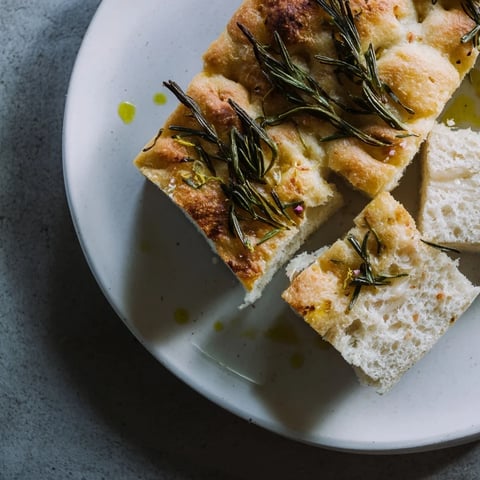 Golden, sliced Holiday Bread focaccia with fresh rosemary, ready to be served.