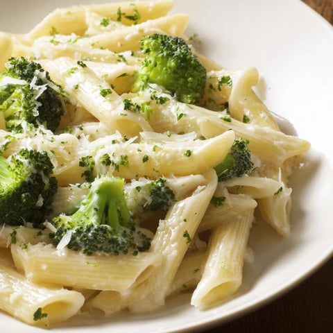 A steaming bowl of Cream Cheese Garlic Pasta with vibrant green broccoli florets and parsley.