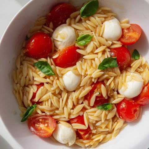 Vibrant Caprese Orzo Salad with juicy tomatoes, creamy mozzarella, and a refreshing balsamic dressing.