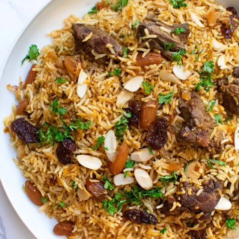 Fluffy Kabsa rice with tender lamb, golden raisins, almonds, and aromatic spices ready to eat.