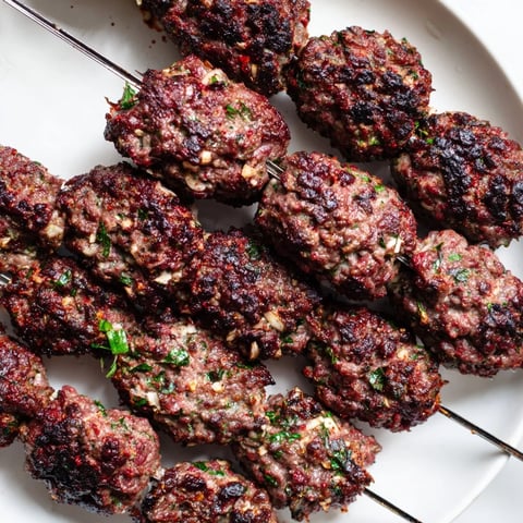 Smoky Iraqi Kebab Tikka skewers sizzling on the grill, a delicious main course with perfectly charred edges.