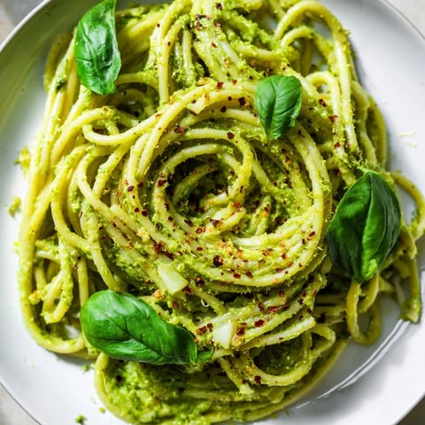 Creamy smashed avocado pasta tossed with lime zest and chili flakes, served warm in a white bowl with fresh basil.