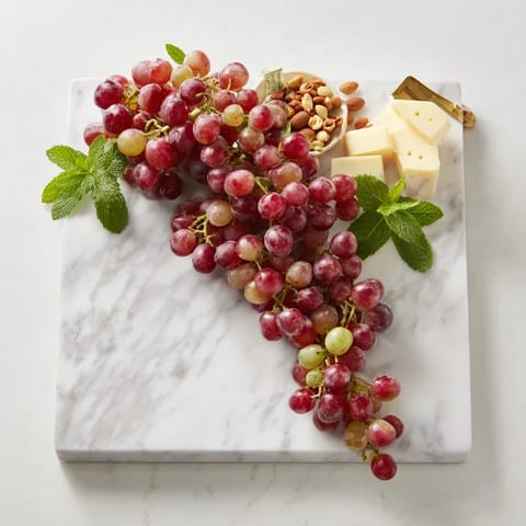 Juicy red and green grapes cascade artfully off a serving board, ready for a refreshing snack.