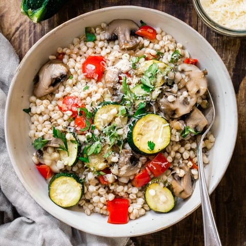 Golden roasted vegetables and creamy pearled barley garnished with fresh parsley for a comforting vegetarian dinner.