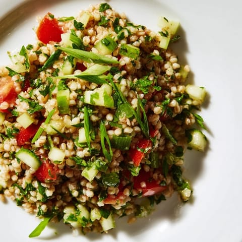 Close-up view of fluffy Bulgur Wheat Salad Tabbouleh served in a white bowl, garnished with mint and a lemon wedge.