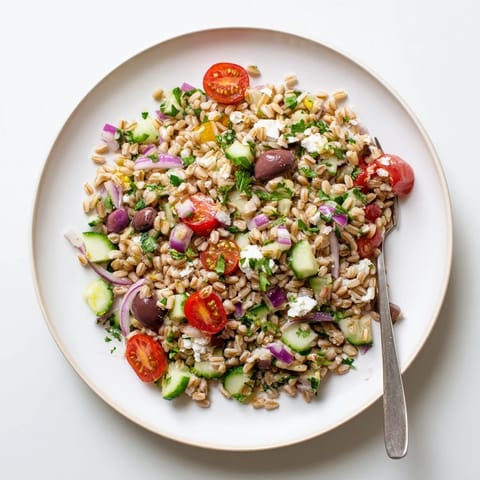 Creamy feta crumbles atop Farro Salad Mediterranean, paired with fresh parsley, red onion, and a zesty vinaigrette on a rustic serving platter.