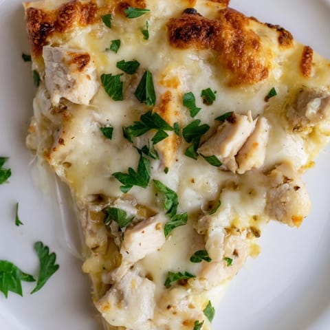 A freshly baked Chicken Alfredo Pizza with a golden crust, topped with creamy Alfredo sauce, diced chicken, and a blend of mozzarella and Parmesan.