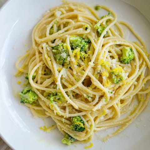 A close-up of One-Pot Lemon Broccoli Pasta in a white bowl, with vibrant green broccoli florets and al dente spaghetti coated in a silky, garlic-infused sauce.