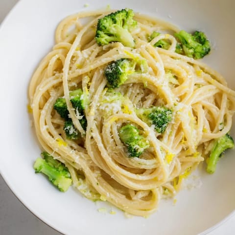 Overhead view of One-Pot Lemon Broccoli Pasta garnished with fresh basil, lemon zest, and grated Parmesan, served alongside a crisp green salad for a spring meal.