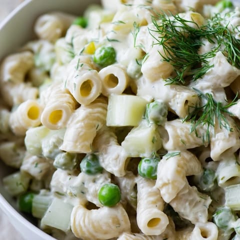 A chilled bowl of Creamy Dill Pickle Pasta Salad, featuring crisp celery and red onion in a zesty dressing for a picnic side.