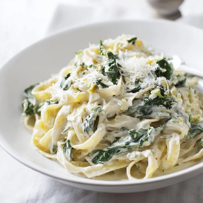 A steaming bowl of Creamy Greek Yogurt Spinach Alfredo Pasta, the silky sauce clinging to perfectly cooked linguine.