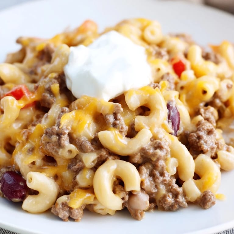 Hearty one-pot chili mac with rich red sauce, topped with cheddar cheese, ready to be devoured.