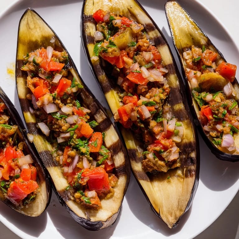 A close-up of Imam Bayildi, showing the baked eggplant halves bursting with a vibrant, flavorful stuffing.