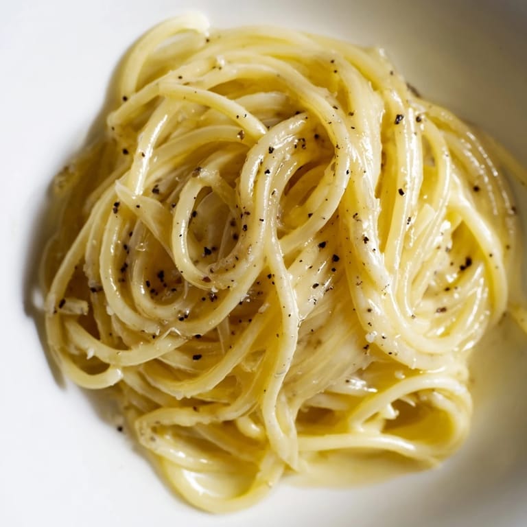 Steaming Spaghetti Cacio e Pepe served in a rustic bowl, topped with a snowfall of extra Pecorino.