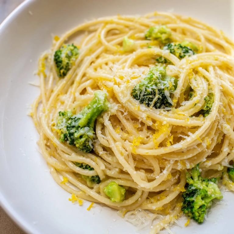 A rustic skillet of One-Pot Lemon Broccoli Pasta steaming gently, showcasing tender broccoli florets and glossy pasta strands glistening with olive oil and lemon juice.