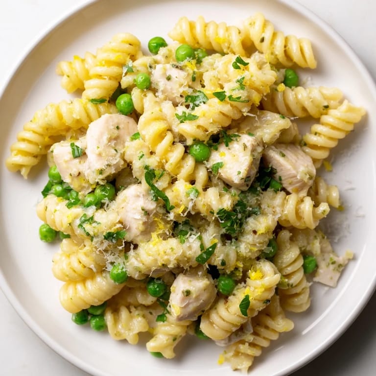 Family-style serving of Garlic Butter Chicken & Pea Pasta topped with fresh parsley and Parmesan, perfect for a cozy dinner.