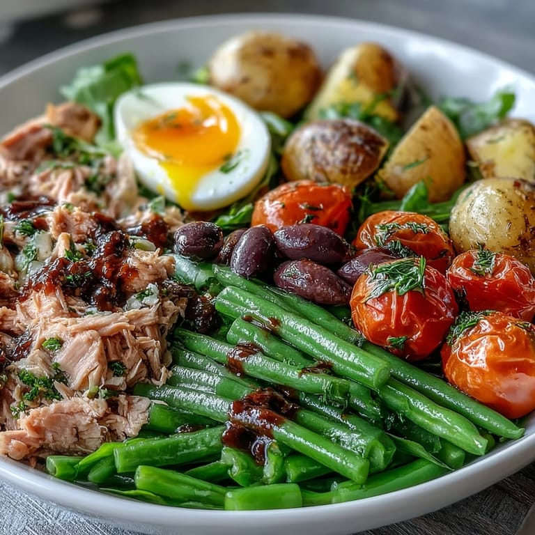 Colorful Spring Niçoise Salad showcasing seasonal vegetables, creamy potatoes, and tuna, served with a tangy red wine and Dijon mustard dressing.