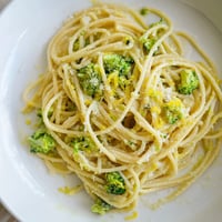A close-up of One-Pot Lemon Broccoli Pasta in a white bowl, with vibrant green broccoli florets and al dente spaghetti coated in a silky, garlic-infused sauce.