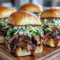 Savory BBQ brisket piled high on soft slider buns, topped with tangy sauce and crunchy slaw for a party-ready bite.